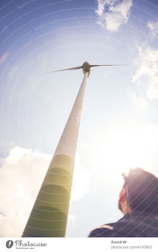 Man standing in front of a wind turbine windmills wind power Future Innovative power supply co2 eco-power Climate protection Climate change Sustainability