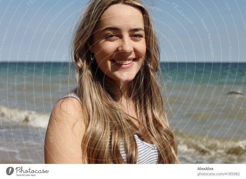 Beautiful blonde girl standing on the beach of the Baltic Sea looking at the camera and laughing Girl Smiling joyfully Landscape by Blonde Joy Exterior shot