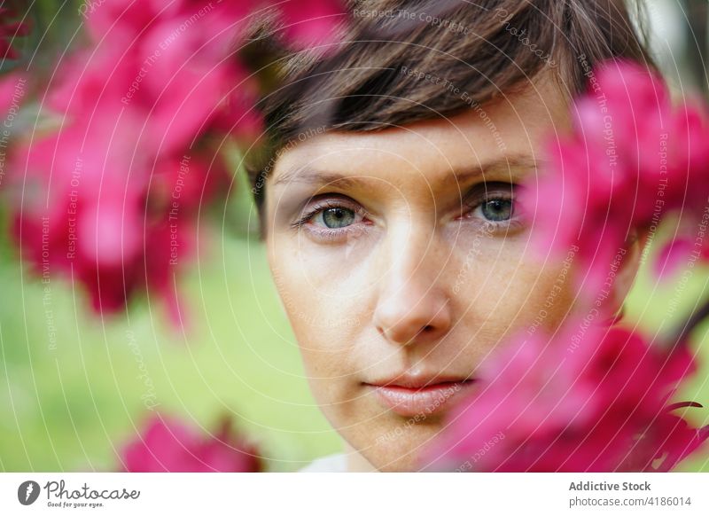 Tranquil adult lady resting in garden among blooming flowers woman recreation pensive calm nature idyllic harmony peaceful relax serene female short hair