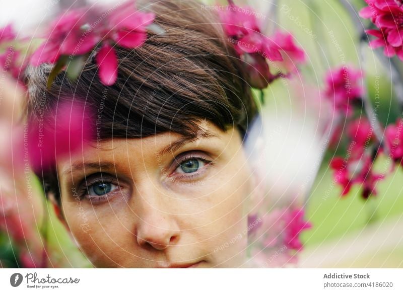 Tranquil adult lady resting in garden among blooming flowers woman recreation pensive calm nature idyllic harmony peaceful relax serene female short hair