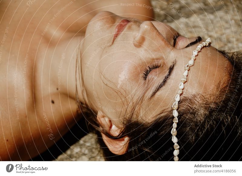 Calm woman lying on sandy seashore with seashells on face sunbath beach eyes closed bead relax peaceful holiday nature summer female young rest vacation