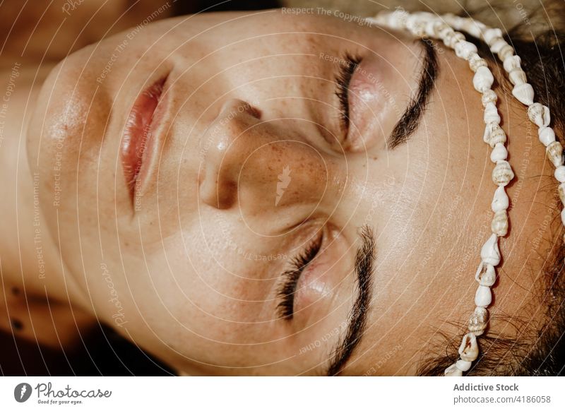 Calm woman lying on sandy seashore with seashells on face sunbath beach eyes closed bead relax peaceful holiday nature summer female young rest vacation