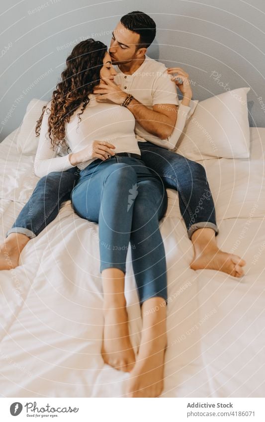 Gentle couple embracing on bed at home embrace tender bedroom kiss forehead gentle relationship together weekend soft fondness affection bonding cuddle romantic