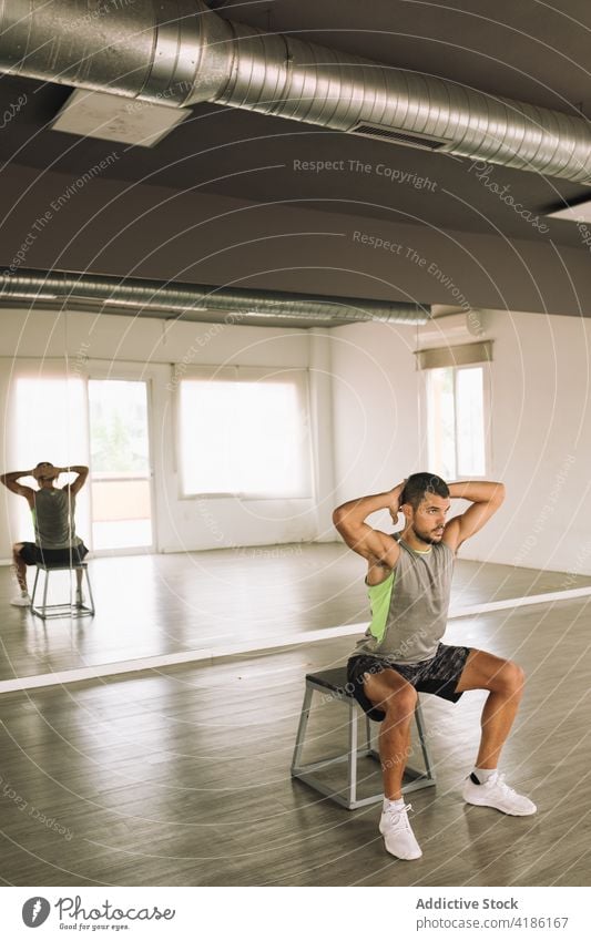 Young sporty guy doing squats on step platform in studio man one leg squat training workout exercise energy endurance physical wellbeing power activity male