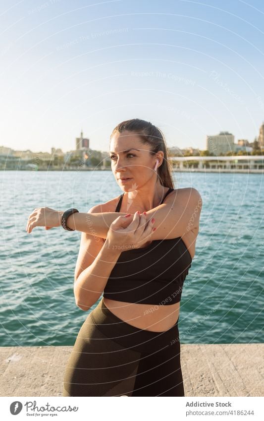 Sporty woman exercising on embankment workout exercise stretch training fitness warm up sport female waterfront wellness healthy wellbeing athlete vitality