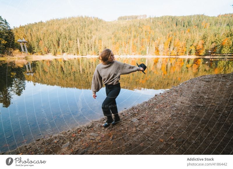 Female traveler walking on lake coast against trees shore reflection nature active woman trip vitality energy tourist journey autumn vacation water mirror