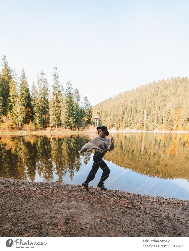 Female traveler running on lake coast against trees shore reflection nature active woman trip vitality energy tourist journey autumn vacation water mirror