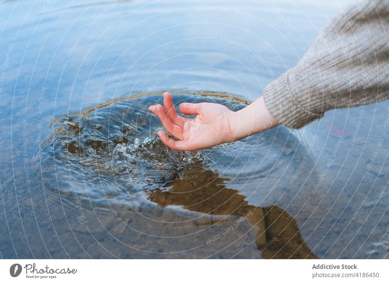 Anonymous tourist touching pure lake water from shore traveler reflection nature vacation mirror trip woman style journey vegetate bright coast weekend female