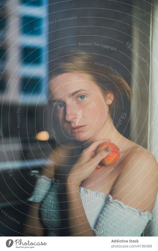 Beautiful woman with peach through the glass dreamy reflection snack kitchen serene positive peaceful feminine counter tranquil charming bare shoulders