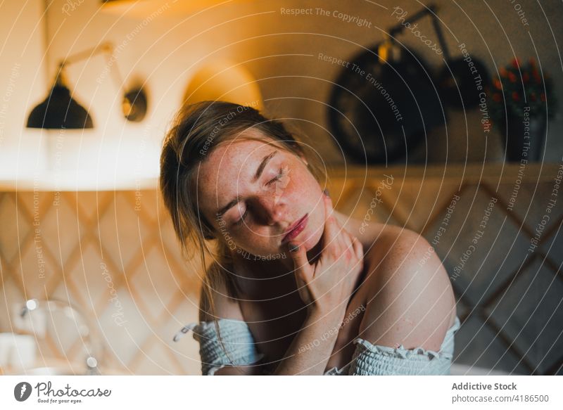 Serene woman touching face gently in kitchen serene dreamy eyes closed touch face tender gentle sensitive feminine harmony peaceful beautiful charming young