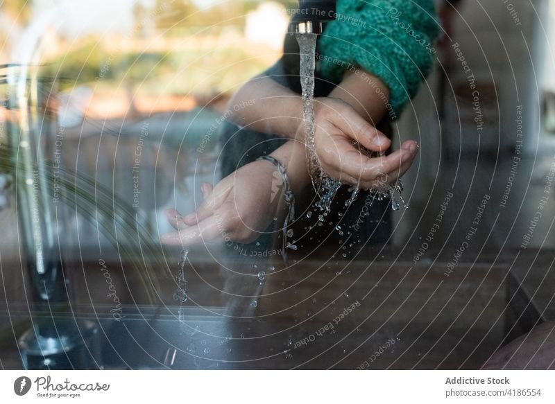 Child washing hands under water in sink child hygiene kitchen tap wet kid healthy splash faucet aqua fresh clean liquid sanitary routine domestic at home stream