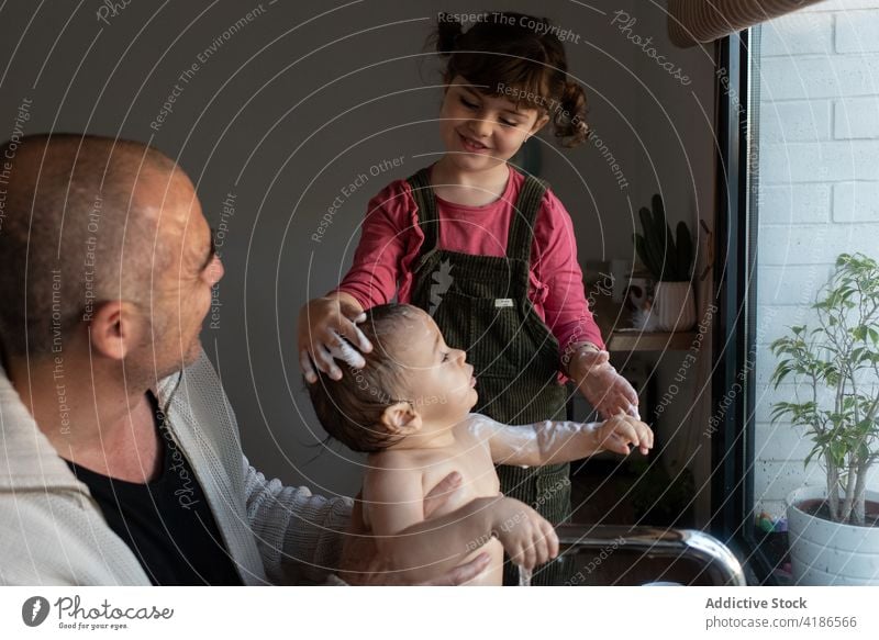 Father and daughter washing baby in sink bath father child help together parent toddler foam kitchen hygiene kid care fatherhood water sister cute girl little