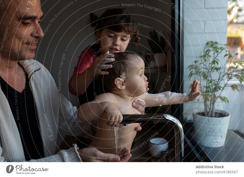 Father and daughter washing baby in sink bath father child help together parent toddler foam kitchen hygiene kid care fatherhood water sister cute girl little