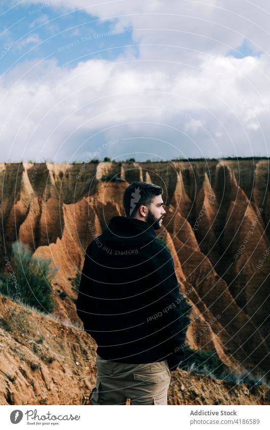 Male traveler contemplating canyon during trip admire nature highland landscape vacation journey man sky cloudy gorge tourist contemplate mountain air