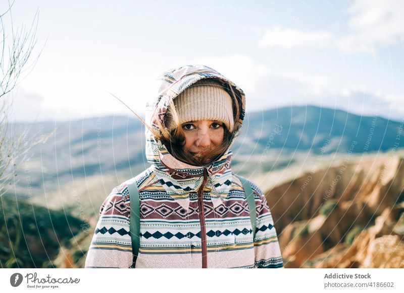 Female trekker against ridges under cloudy sky in sunlight mount nature highland vacation travel sincere woman portrait traveler mountain enjoy trip