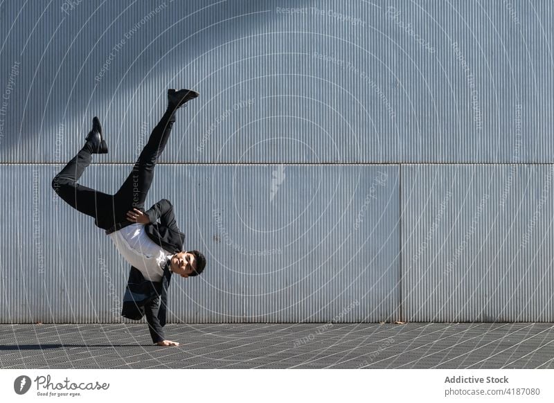 Ethnic businessman performing breakdance handstand on street break dance trick move entrepreneur formal suit male ethnic asian urban city executive manager