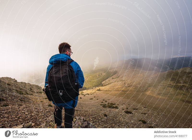 Unrecognizable backpacker exploring mountains on walkway in fog trekker explore nature route direction pathway highland man sky mist pena de la cabra rucksack