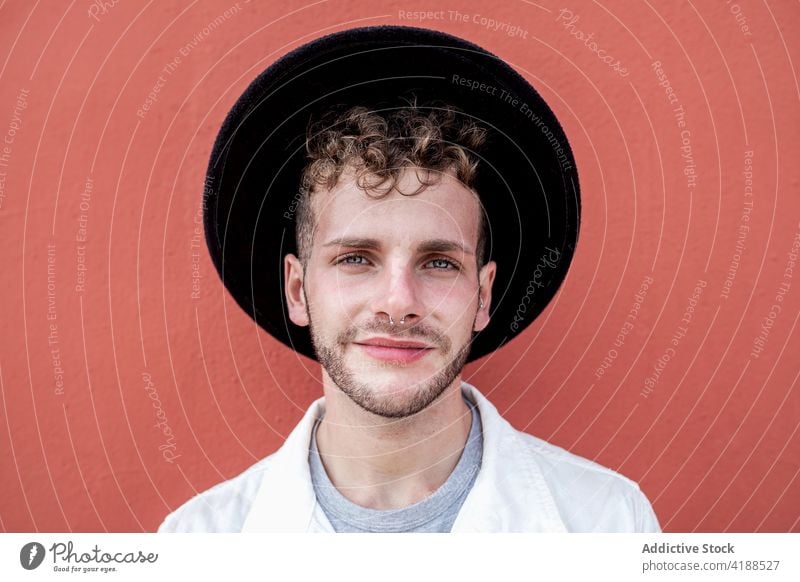 Happy young guy smiling against red background man smile confident content style trendy personality adjust hat relax street happy cool street style cheerful