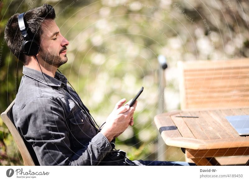 Man listening to music on his mobile phone - relaxation Music stream Listening Cellphone Headphones To enjoy time-out chill Nature Beautiful weather Lifestyle