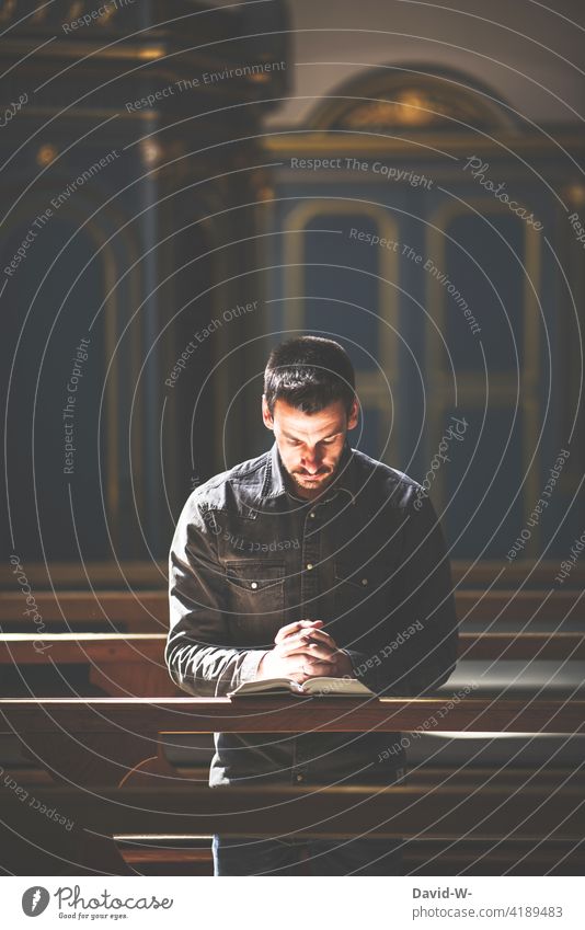 Man kneels praying in a pew of a church and is illuminated by sunlight Church Belief Kneel Sunlight Prayer Light Hope Church pew believe Grief Spirituality