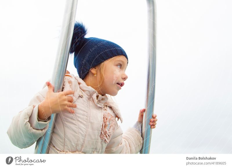 girl in autumn clothes spins and balances on modern metal carousel go motion season active equipment outside preschool care funny beautiful fall playground