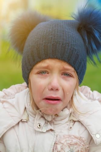 Sad crying offended girl cold autumn outdoor. Concept of upset child preschooler european desperation care cheerful hat hungry walking pom-pom lifestyle