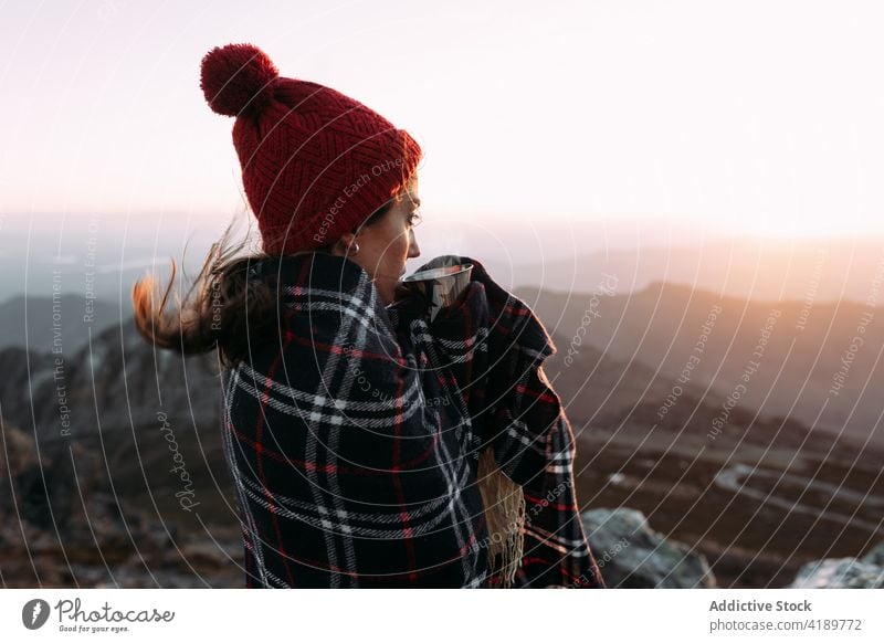 Traveler standing on rock in mountains traveler viewpoint observe highland hiker wool cap hot coffee beverage enjoy cup admire blanket explore amazing scenery