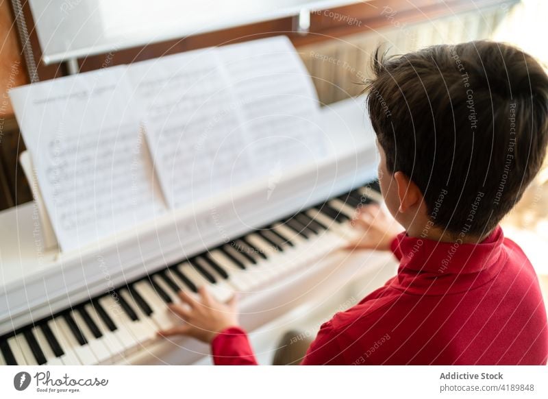 Boy playing piano at home child boy rehearsal song music musician note melody kid study sit talent instrument skill practice sound hobby pianist perform rhythm