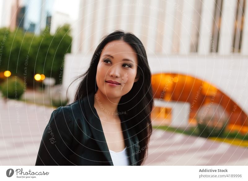 Asian businesswoman walking in street in downtown city entrepreneur megapolis well dressed style female asian ethnic urban modern elegant skyscraper building