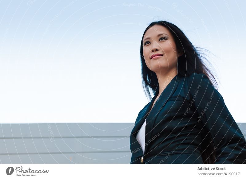 Ethnic businesswoman walking along street near building confident style entrepreneur urban well dressed city female asian ethnic sidewalk pavement stroll