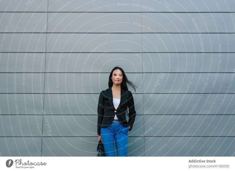 Ethnic businesswoman walking along street near building confident style entrepreneur urban well dressed city female asian ethnic sidewalk pavement stroll