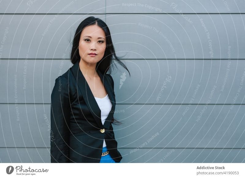 Ethnic businesswoman walking along street near building confident style entrepreneur urban well dressed city female asian ethnic sidewalk pavement stroll