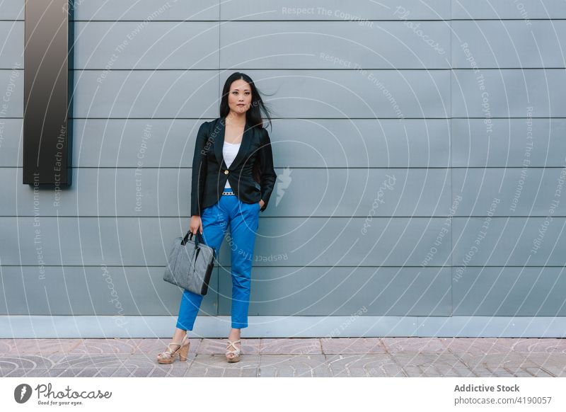 Ethnic businesswoman walking along street near building confident style entrepreneur urban well dressed city female asian ethnic sidewalk pavement stroll