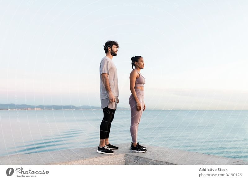 sportspeople admiring river from embankment at sunset contemplate nature cloudy sky healthy lifestyle fit wellness woman together partner enjoy ripple water