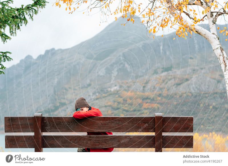 Woman sitting on bench in majestic autumn park woman admire mountain lakeside rest enjoy picturesque severe peaceful ridge fall range calm outerwear season