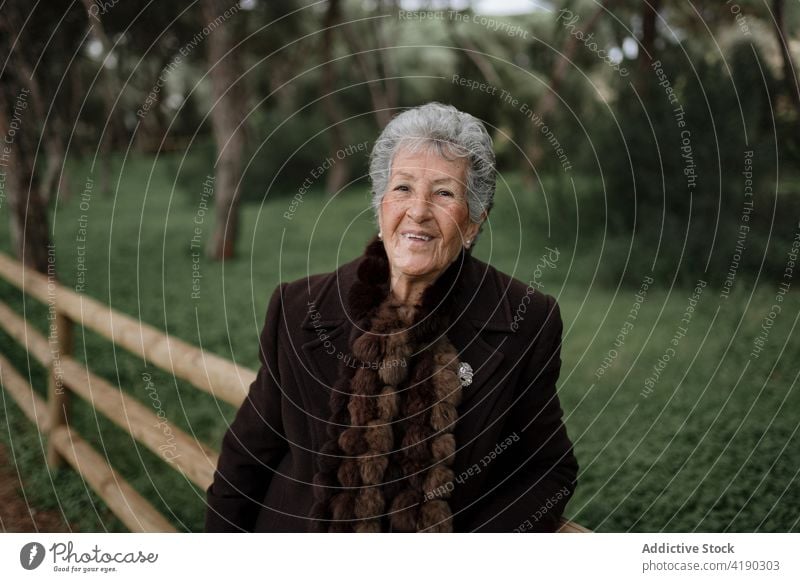 Senior lady looking at camera from boardwalk woman admire seascape beach traveler enjoy nature vacation relax ocean female elderly casual wooden pier viewpoint