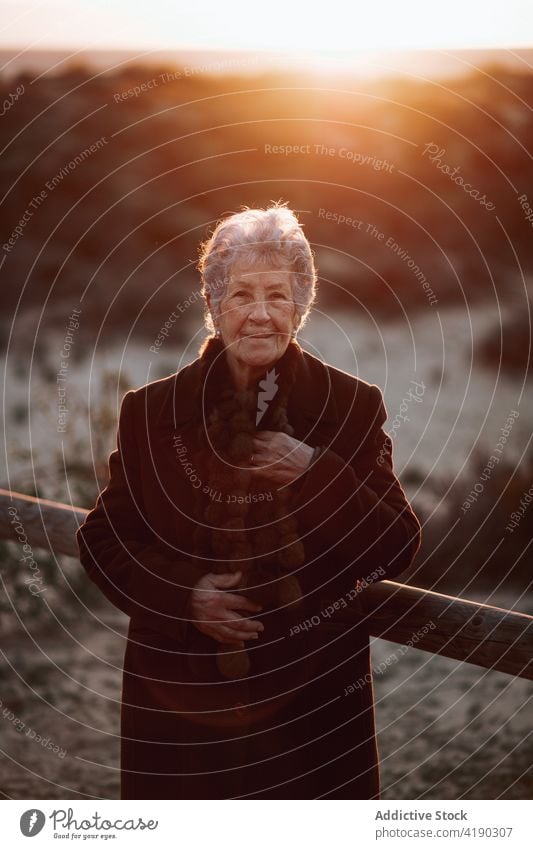 Senior lady admiring sunset over ocean from boardwalk woman admire seascape beach traveler enjoy nature vacation relax female elderly casual wooden pier