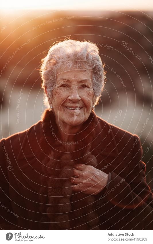 Senior lady admiring sunset over ocean from boardwalk woman admire seascape beach traveler enjoy nature vacation relax female elderly casual wooden pier