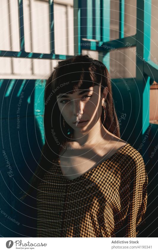 Fashionable young ethnic lady standing near green wall and looking at camera woman pensive thoughtful style cool fashion calm street dreamy gorgeous brick wall