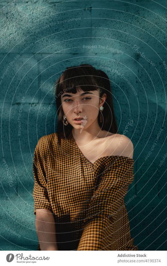 Fashionable young ethnic lady standing near green wall and looking at camera woman pensive thoughtful style cool fashion calm street dreamy gorgeous brick wall