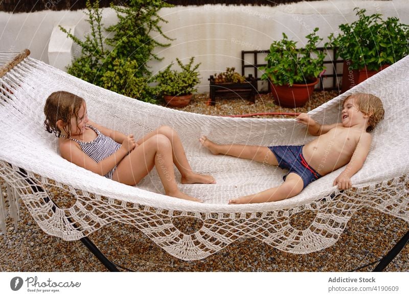 Adorable little siblings having fun while lying together in hammock children play holiday joy childhood cheerful cute sister brother kid toddler adorable smile