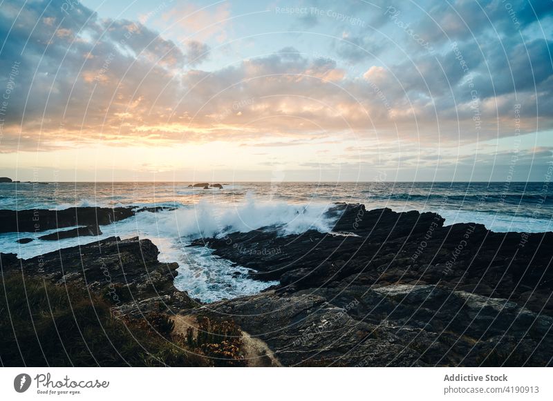 Rocky seashore washed by foamy waves steep rock slope cliff splash stone coast water seaside grass nature coastline scenery rocky turquoise wild seacoast ripple