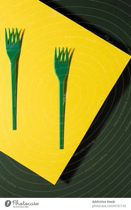 Plastic and recyclable forks on green background recycle eco friendly natural reuse reduce zero waste cutlery carton refuse colorful sheet similar plastic