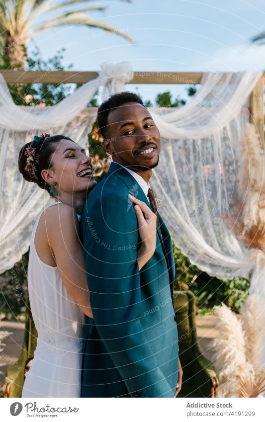 Cheerful newlywed couple hugging in garden cheerful bride groom wedding love together multiethnic multiracial diverse black african american embrace cuddle