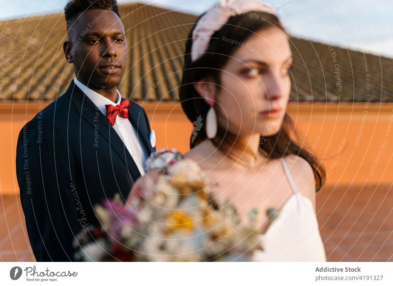 Multiethnic newlywed couple on terrace tender wedding bouquet flower bride groom together black african american multiracial multiethnic diverse bridal elegant