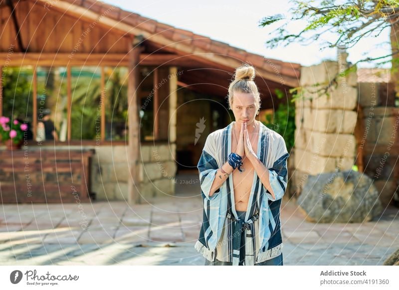 Hipster man with Praying hands on pavement namaste yoga spirit wellness healthy lifestyle vitality hipster portrait praying hands stretch wellbeing building old