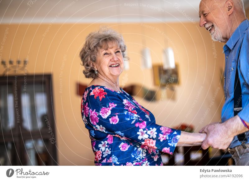 Happy senior couple dancing together at home real people candid genuine woman mature female love bonding Caucasian elderly house old aging domestic life