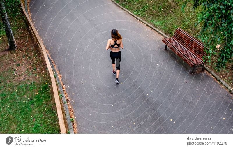 Aerial view of female runner backwards top view woman slender running urban park asphalt persevere sport overhead aerial view athlete fitness healthy exercise