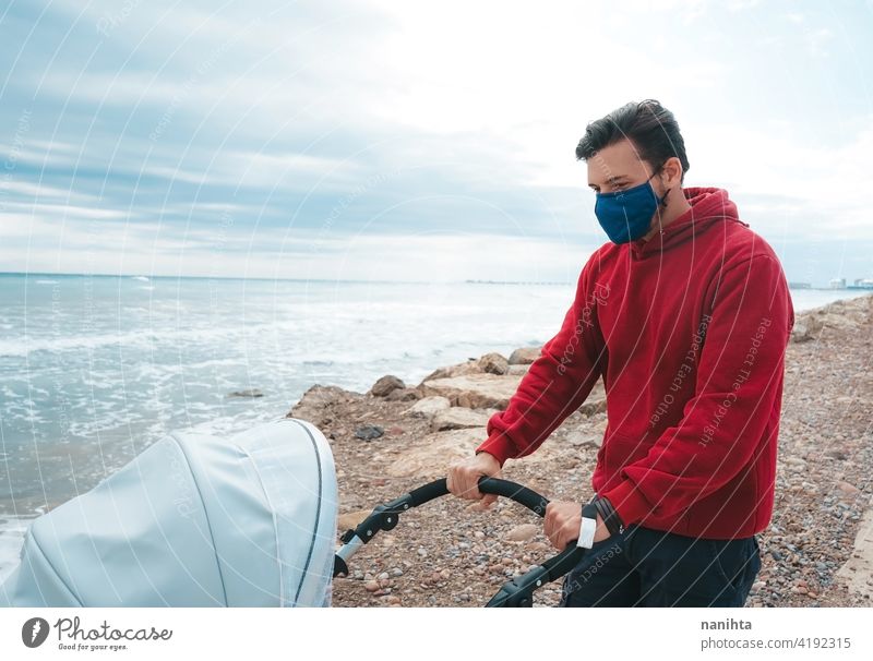 Dad walking with his baby while use his mobile phone pram dad holidays covid coronavirus flu mask allergy face mask health sunny summer summertime