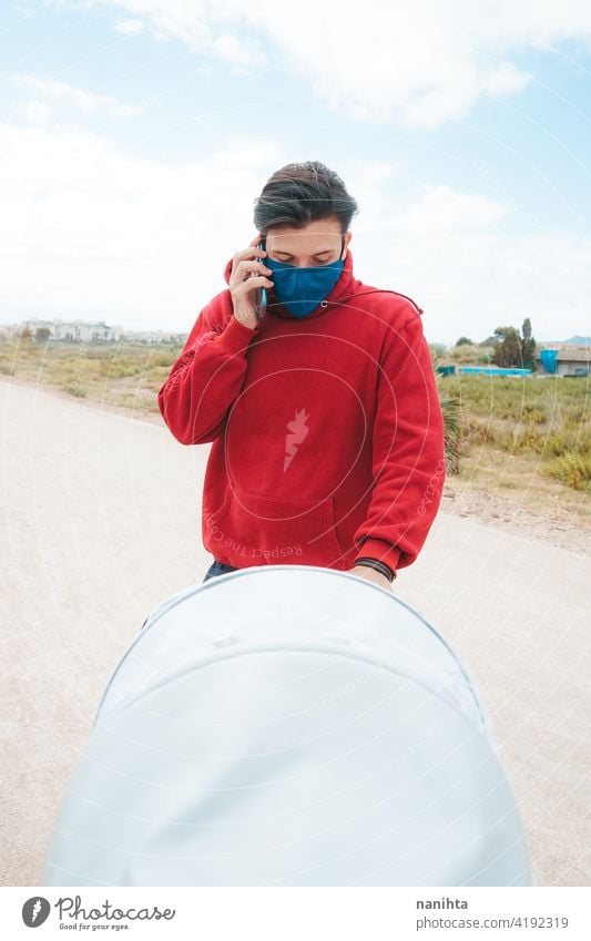 Dad walking with his baby while use his mobile phone pram dad holidays covid coronavirus flu mask allergy face mask health sunny summer summertime